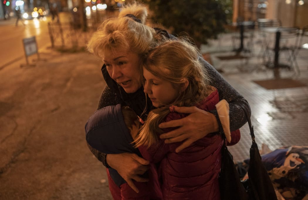 An Ukrainian refugee from from the Black Sea port city of Odessa, hugs two children as they arrive in Athens by bus, following the Russian invasion of Ukraine on March 6, 2022.