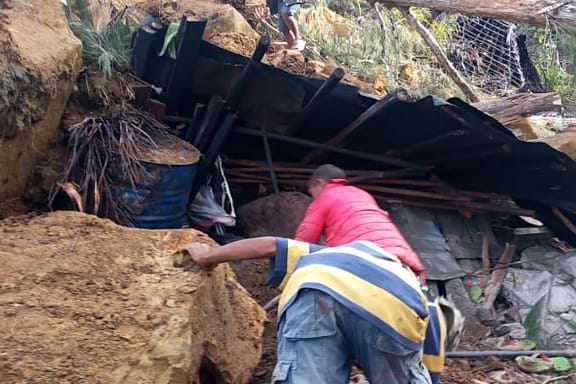 Locals look into a demolished house at the site of a landslide at Yambali Village in the region of Maip Mulitaka, in Papua New Guinea's Enga Province on May 25, 2024.