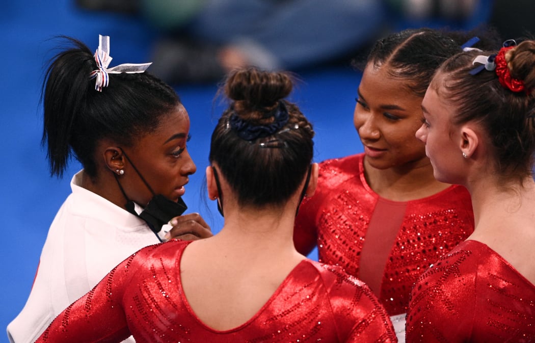 USA's Simone Biles (L) talks to teammates during the artistic gymnastics women's team final during the Tokyo 2020 Olympic Games at the Ariake Gymnastics Centre in Tokyo on July 27, 2021.