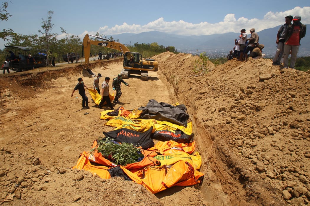 Officers bring the bodies of victims of the earthquake and tsunami to bury them in Palaroa village, in the city of Palu, Central Sulawesi, Indonesia.