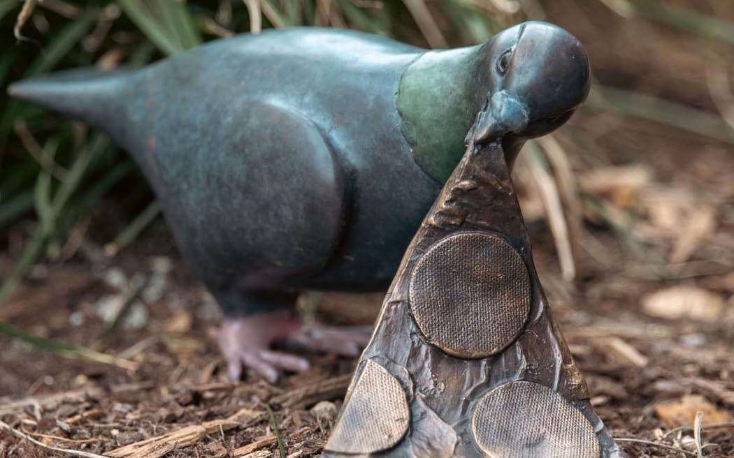 A bronze statue depicting a pigeon carrying a slice of pizza.