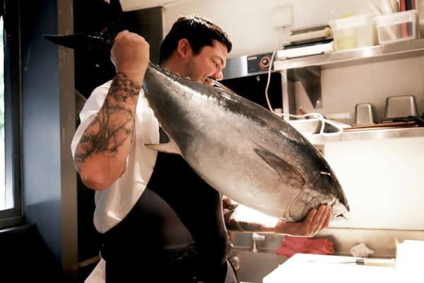Emmelyn Restaurant executive chef Caleb Carter holds up a bluefin tuna fish as he prepares to cut it.