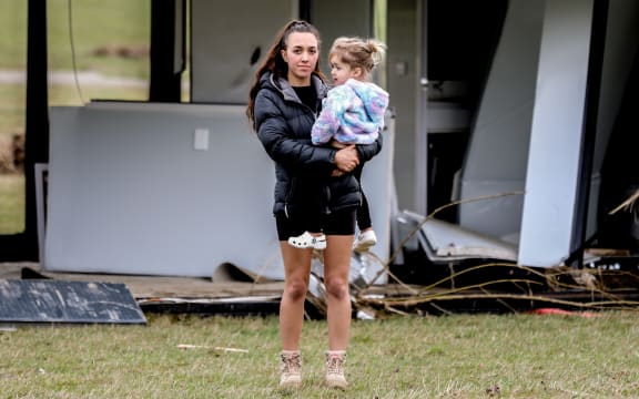 Blue Malosso and her child in front of her home which was picked up and taken hundreds of metres by floodwaters.