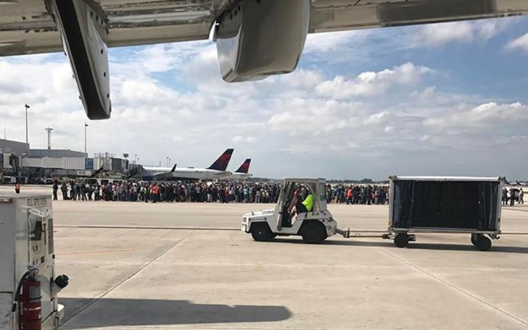 Passengers gather on the tarmac of the Fort Lauderdale-Hollywood airport in Florida after a gunman opened fire.