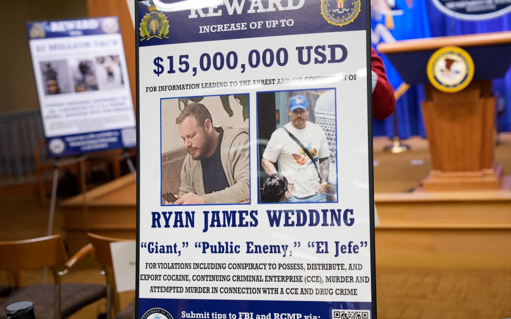 WASHINGTON, DC - NOVEMBER 19: A reward poster for the arrest of Ryan James Wedding is visible following a news conference announcing the indictment of a former Olympic snowboarder Ryan Wedding, charging him with murder and money laundering in connection to a drug trafficking organization at the Justice Department on November 19, 2025 in Washington, DC. The Justice Department announced a fifteen-million-dollar reward for information leading to the arrest of Ryan James Wedding, the leader of a criminal drug organization who smuggled large quantities of cocaine through Colombia and Mexico for distribution in the United States and Canada.   Andrew Harnik/Getty Images/AFP (Photo by Andrew Harnik / GETTY IMAGES NORTH AMERICA / Getty Images via AFP)