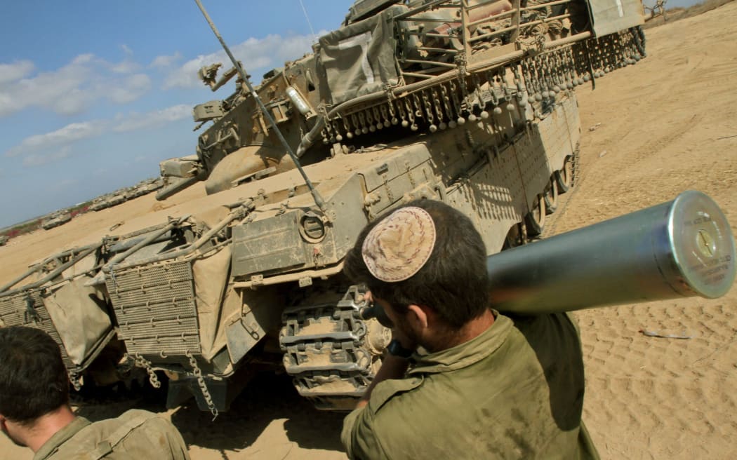 An Israeli soldier carries a shell on his shoulder as troops prepare ammunition along the border between Israel and the Hamas-controlled Gaza Strip.