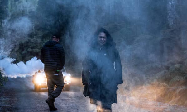 Kath Akuhata-Brown (Ngāti Porou) standing amid fog on a road in bush, Hari Hari, West Coast, South Island.
