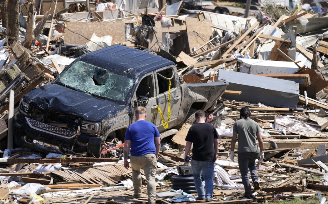 Local residents walk among the debris from tornado damaged homes, Wednesday, May 22, 2024, in Greenfield, Iowa. (AP Photo/Charlie Neibergall)