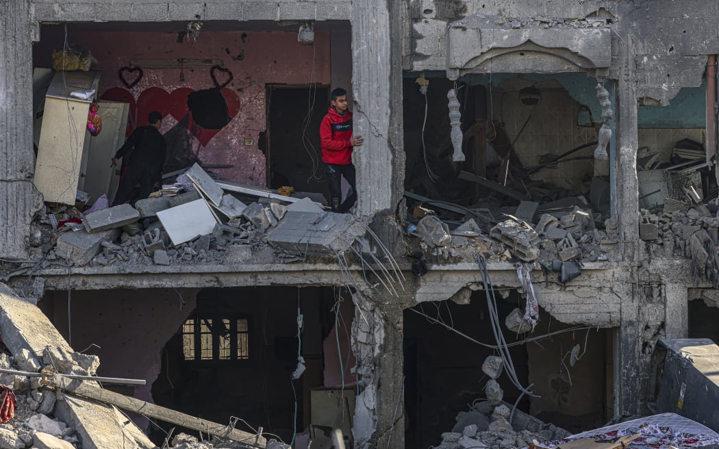 Palestinians inspect the damage in the rubble of a building where two hostages were reportedly held before being rescued during an operation by Israeli security forcess in Rafah, on the southern Gaza Strip on February 12, 2024, amid ongoing battles between Israel and the militant group Hamas. Israel announced on February 12 the rescue of two hostages in the southern Gaza city of Rafah, where the Hamas-run health ministry said "around 100" Palestinians including children were killed in heavy overnight air strikes. (Photo by SAID KHATIB / AFP)