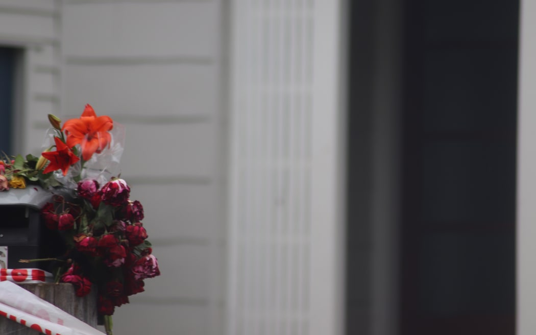 Flowers have been placed by the letterbox at the house where a woman was killed in Napier on Friday night.