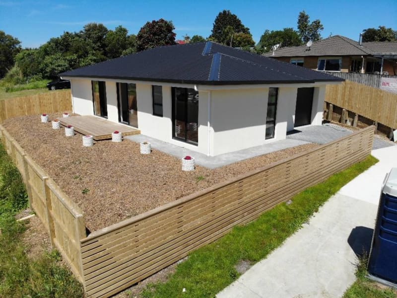 A cream coloured house with a dark coloured roof and a wooden fence.