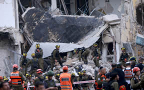 Rescuers sift through the debris of a damaged building in the Israeli city of Tel Aviv after a fresh barrage of Iranian rockets on 16 June, 2025.