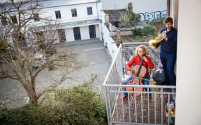 dpatop - 22 March 2020, Saxony, Dresden: The musical couple Karoline Strobl and Zoltán Mácsai play the "Ode to Joy" with cello and horn on their balcony.