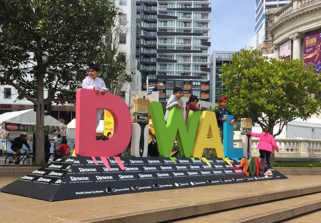 Children clamber over Diwali sign to pose for photograhs.