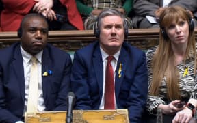 A video grab from footage broadcast by the UK Parliament's Parliamentary Recording Unit (PRU) shows Britain's main opposition Labour Party Foreign Secretary David Lammy (L), Britain's main opposition Labour Party leader Keir Starmer (C) and Britain's main opposition Labour Party deputy leader Angela Rayner (R) listening to Ukraine's President Volodymyr Zelensky as he speaks to them by live video-link in the House of Commons, in London, on March 8, 2022. (Photo by PRU / AFP)