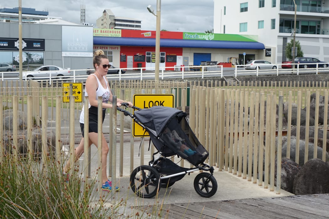 A woman pushes a pram through a chicane at one of the rail crossings on New Plymouth’s Coastal Walkway.