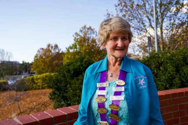 ACT Shirley Club acting coordinator Shirley Towner standing outdoors with Shirley name club badges adorning her.