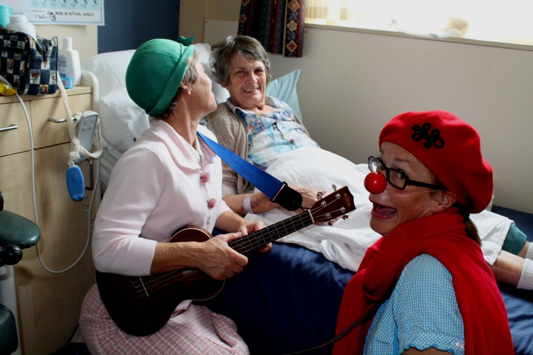 Photo of Clown doctors entertaining Margaret Chelley at Princess Margaret Hospital