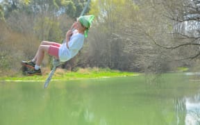 Rosie Glover swings over the Selwyn River. She does not swim anymore because of the toxic green slime covering large stretches of it.