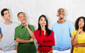 Eight diverse people looking upward with curious expressions
