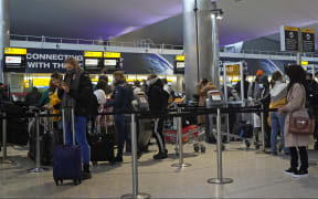 Passengers wearing masks queue at Heathrow Airport in west London on December 21, 2020.