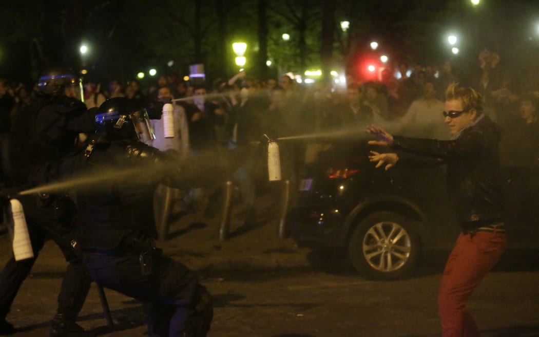 Supporters of the anti-gay marriage movement "La Manif Pour Tous" (Demonstration for all!) clash with riot policemen as they demonstrate on April 17, 2013 in Paris. police officers in riot gear appear to be spraying a protester wearing sunglasses for protection with teargas/