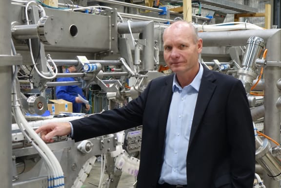 Andrew Arnold, General Manager of Robotics and Automation at Scott Technology, Dunedin stands in front of a large robotic processing machine made of a series of silver pipes