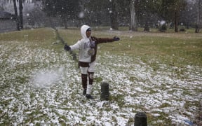 Gabriel Sussman gestures as snow falls in Zoo Lake park in Johannesburg on 10 July 2023.