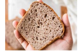 a hand holds up a slice of brown bread