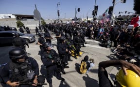 Law enforcement face off with demonstrators during clashes in front of the federal building during a protest following federal immigration operations, in Los Angeles, California on June 8, 2025. US President Donald Trump deployed 2,000 troops on June 7 to handle escalating protests against immigration enforcement raids in the Los Angeles area, a move the state's governor termed "purposefully inflammatory." Federal agents clashed with angry crowds in a Los Angeles suburb as protests stretched into a second night Saturday, shooting flash-bang grenades and shutting part of a freeway amid raids on undocumented migrants, reports said. (Photo by ETIENNE LAURENT / AFP)