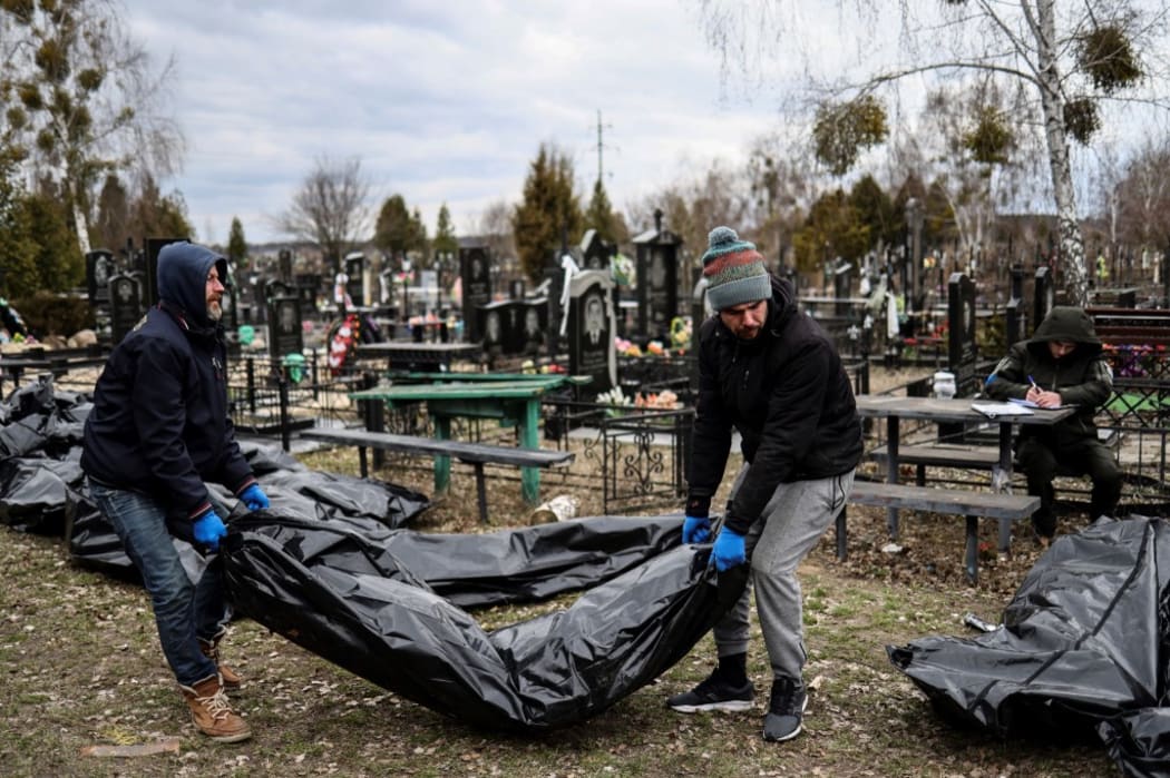 EDITORS NOTE: Graphic content / Workers line up bodies for identification by forensic personnel and police officers in the cemetery in Bucha, north of Kyiv, on April 6, 2022,