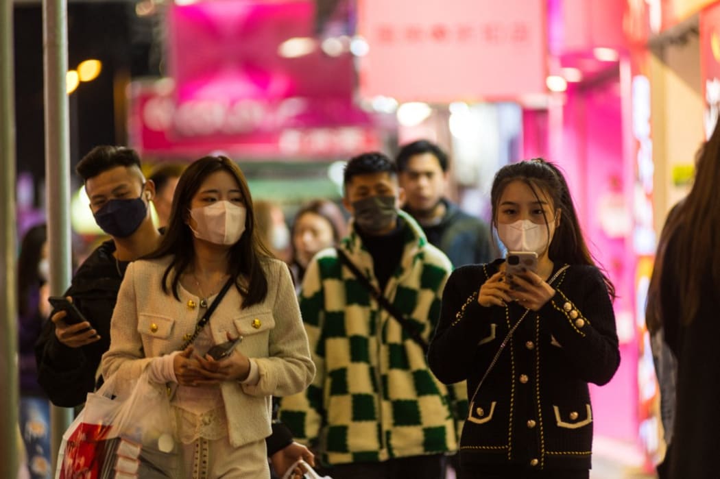 Masked people walk on Sai Yeung Choi South street, in Hong Kong, China, on February 5, 2022, in Hong Kong, China, on February 5, 2022. (Photo by Marc Fernandes/NurPhoto) (Photo by Marc Fernandes / NurPhoto / NurPhoto via AFP)