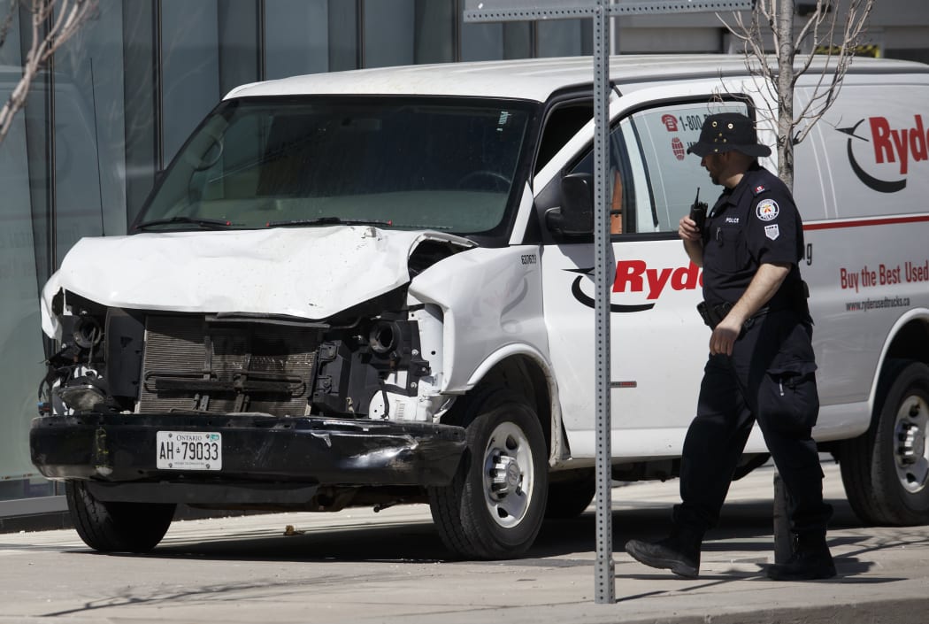 Police inspect a van which mounted the pavement and hit a crowd of pedestrians in Toronto.