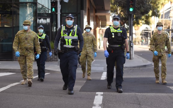 A group of police and soldiers patrol the Docklands area of Melbourne on August 2, 2020, after the announcement of new restrictions to curb the spread of the COVID-19 coronavirus.
