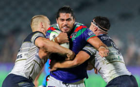 Warriors forward Tohu Harris tries to break through two North Queensland tacklers.