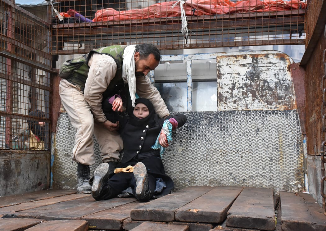 A wounded Syrian woman is helped onto the back of a truck as she flees during the ongoing government forces military operation in Aleppo on 14 December, 2016.