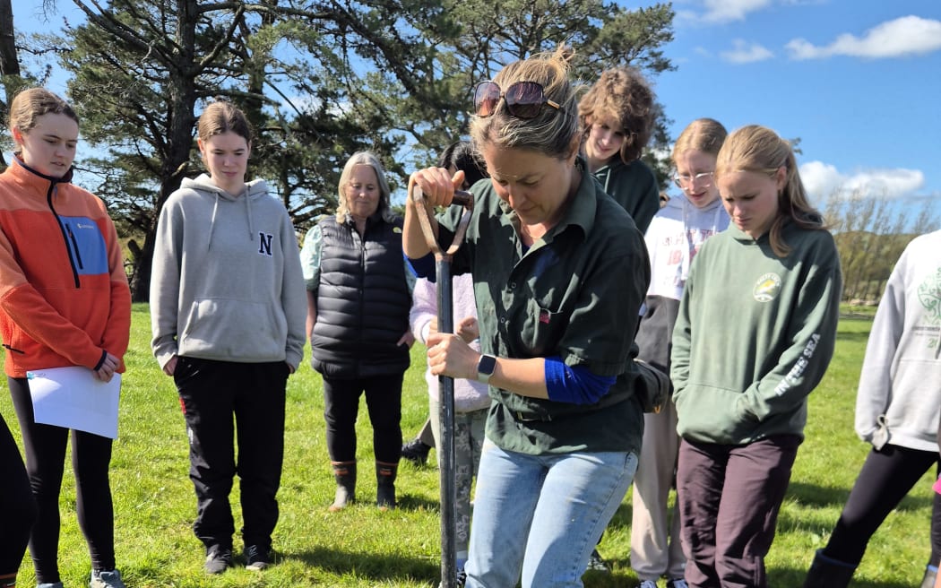 Katie Wyeth shows the students how to get stuck in as part of soil testing on farm.