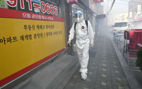 A health official wearing protective gear sprays disinfectant on the street near the Sarang Jeil Church, a new coronavirus infection cluster, in South Korea's capital Seoul.