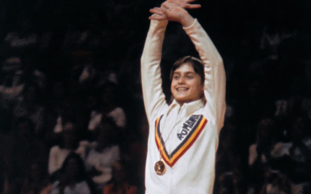 Romanian champion Nadia Comaneci, aged 14, waves on the women' s Olympic uneven bars event podium of the Montreal 1976 Olympic Games on July 24, 1976 in Montreal. Legendary gymnast, during her career Nadia Comaneci captured four Olympic gold medals and was the first to score 10 in her discipline. (Photo by EPU / AFP)