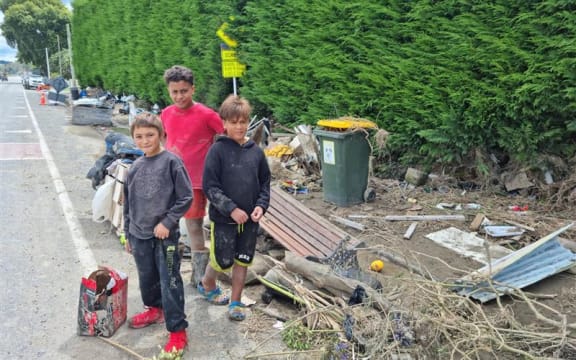 Kids helping move damaged property to the roadside ready for pickup by the Army in Omahu