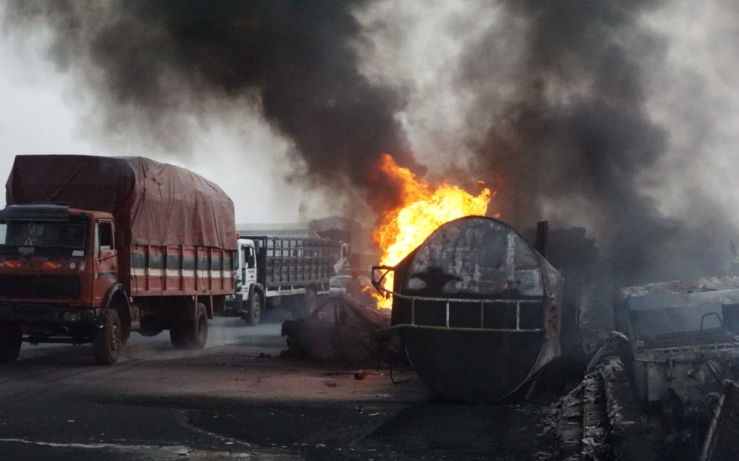 Haulage trucks drive past fuel-ladden tanker which exploded and fell after a collision with a car along Warewa bridge and causing severe traffick gridlock on Lagos Ibadan expressway, the gateway from Lagos, Nigeria's economic hub to other parts of the country in Ogun State, southwest Nigeria on April 2, 2023. (Photo by PIUS UTOMI EKPEI / AFP)