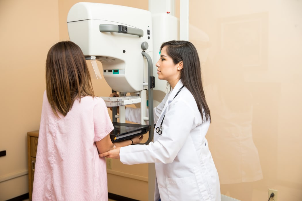 Doctor setting a patient in the correct position to get a mammogram. Breast cancer screening.