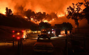 Firefighters conduct a controlled burn to defend houses against flames.