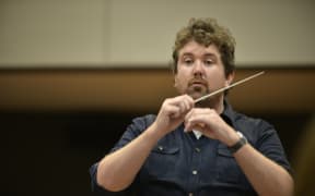 Brass band conductor and player Tom Davoren holds a conductor's baton.
