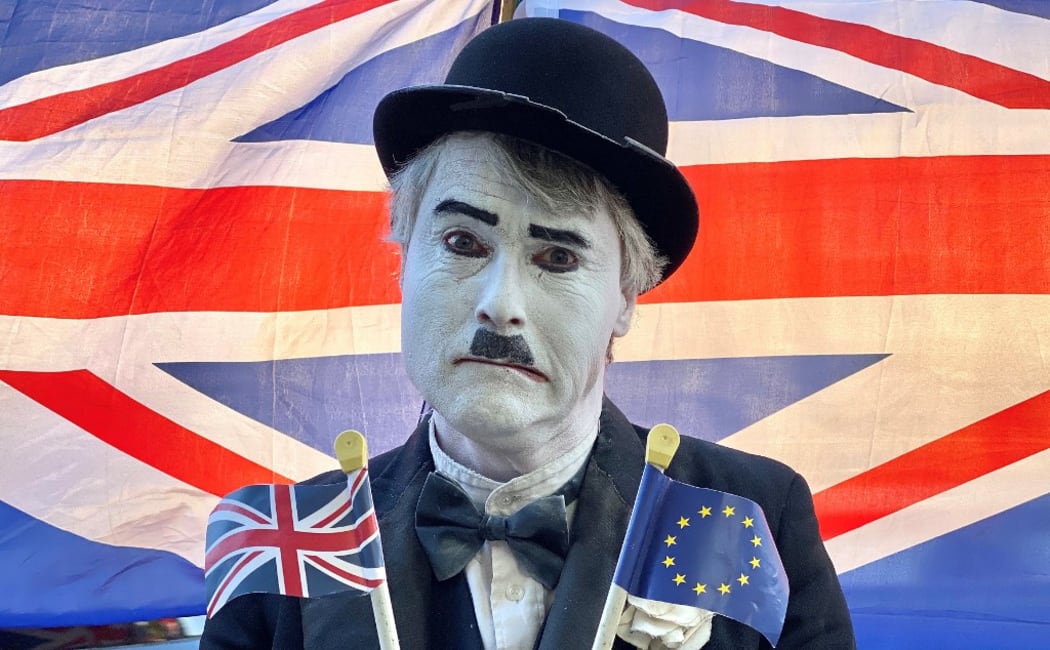 A Brexit activist dressed as the late English comic actor Charlie Chaplin, holds a Union and an EU flag as he protests outside the Houses of Parliament in London on October 22, 2019.