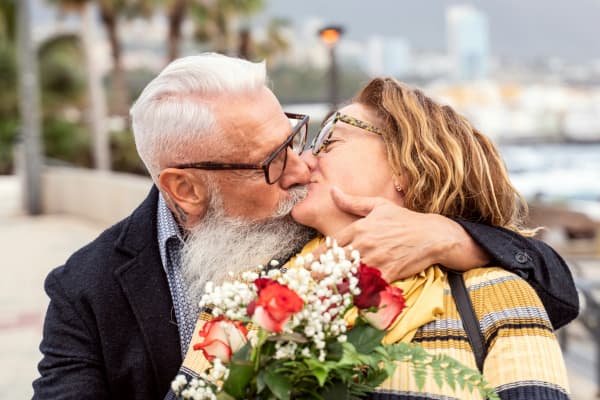 Older couple embracing while holding flowers