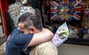 Jono Manielle gives Nicky Perry, owner of Tea and Sympathy, and A Salt and Battery, flowers after the death of Queen Elizabeth II outside Tea & Sympathy in the West Village on September 08, 2022 in New York.