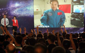 Students ask Wang Yaping questions as she delivers a lesson to them from Tiangong-1 space module in the morning of June 20, 2013.