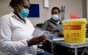 A patient receives a vaccination card after being vaccinated against Covid-19 at the Witkoppen clinic in Johannesburg on 8 December, 2021.