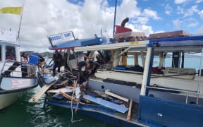 Passengers on the stricken Blue Ferry clamber over wreckage to the safety of the Happy Ferry while others tend to the injured skipper.